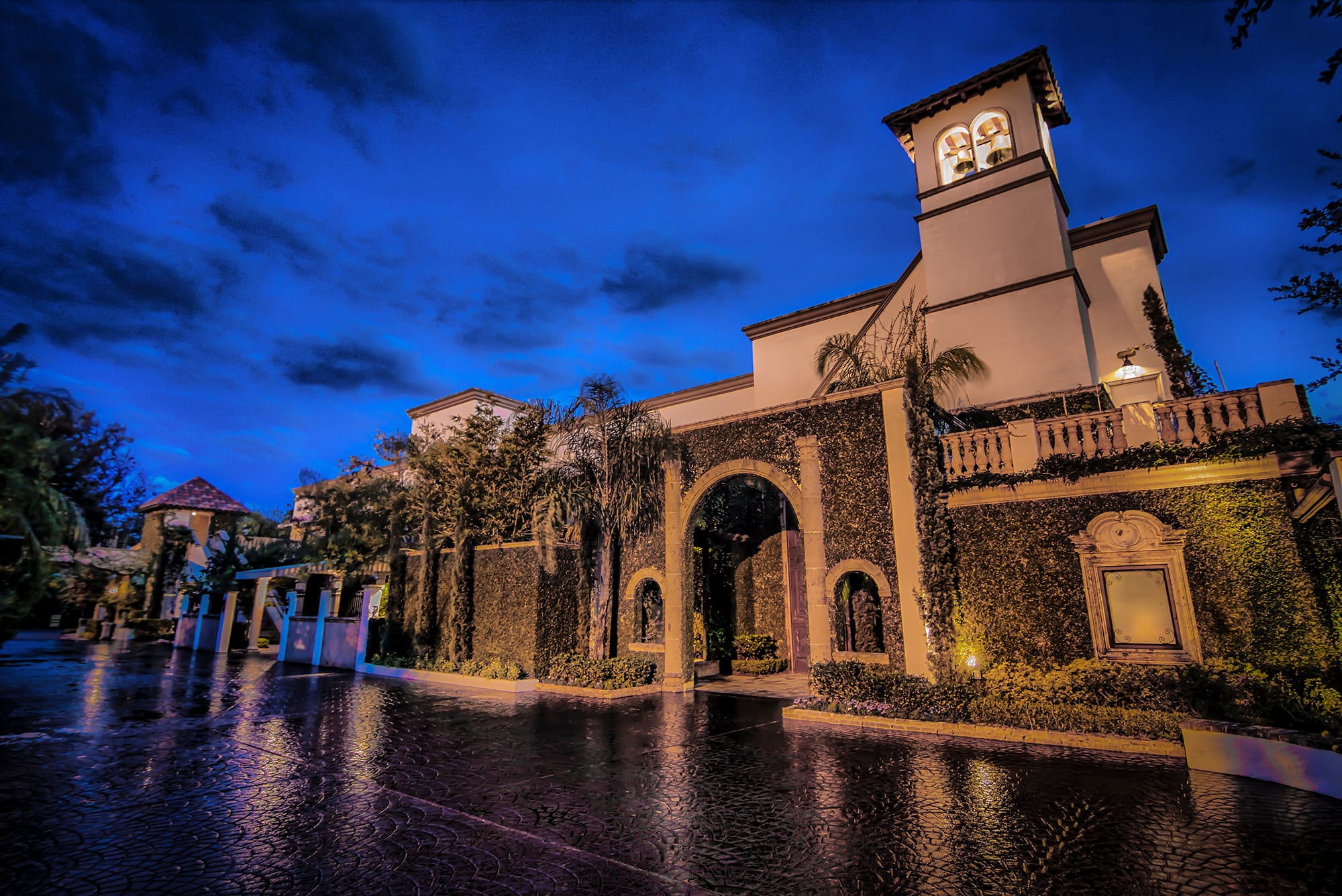 The bell tower and front drive of The Bell Tower on 34th in Houston at dusk